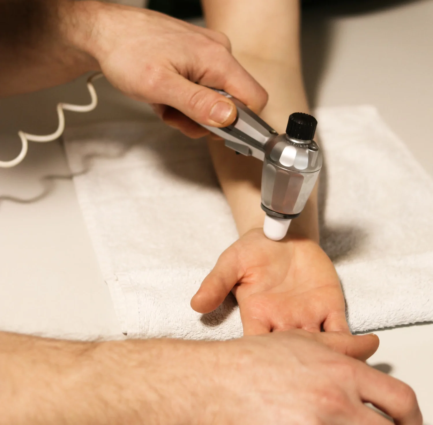 Behandlung mit einem Reflexhammer am Handgelenk
